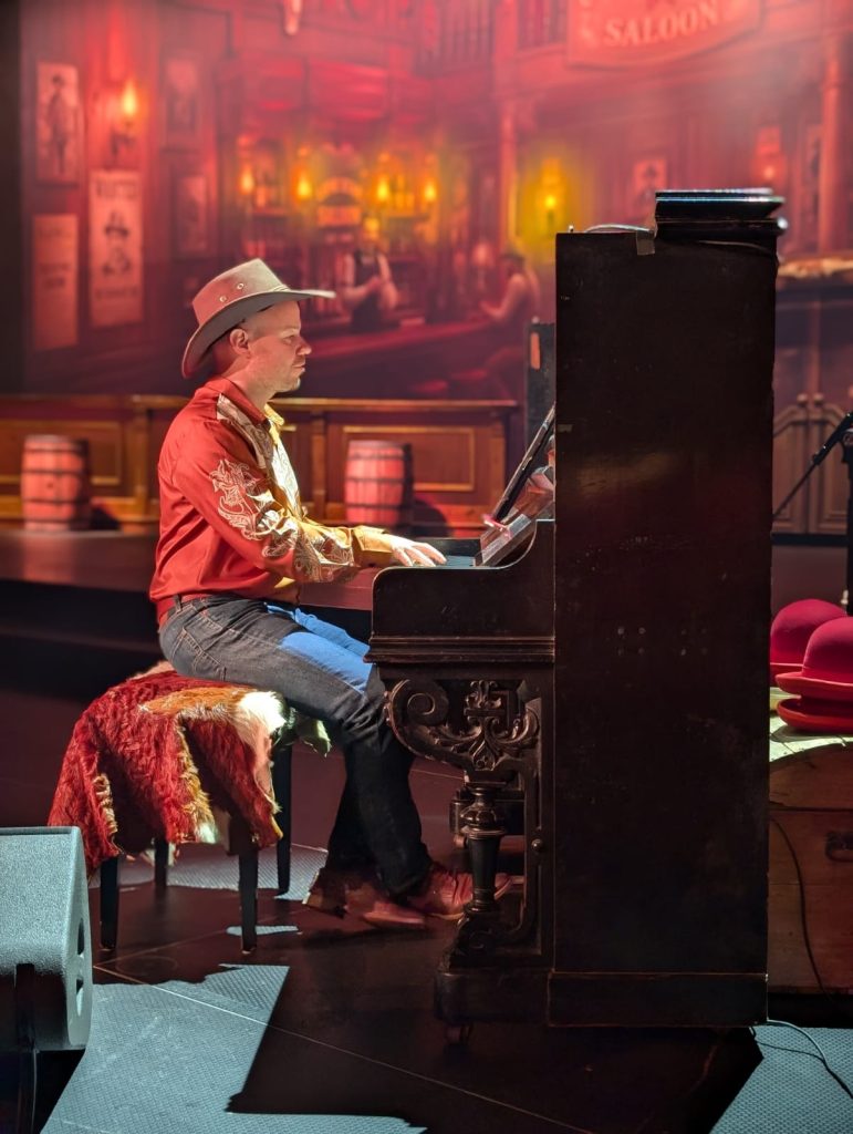 Pianist und Sängerin am alten Klavier in der Saloon-Kulisse der Western-Show